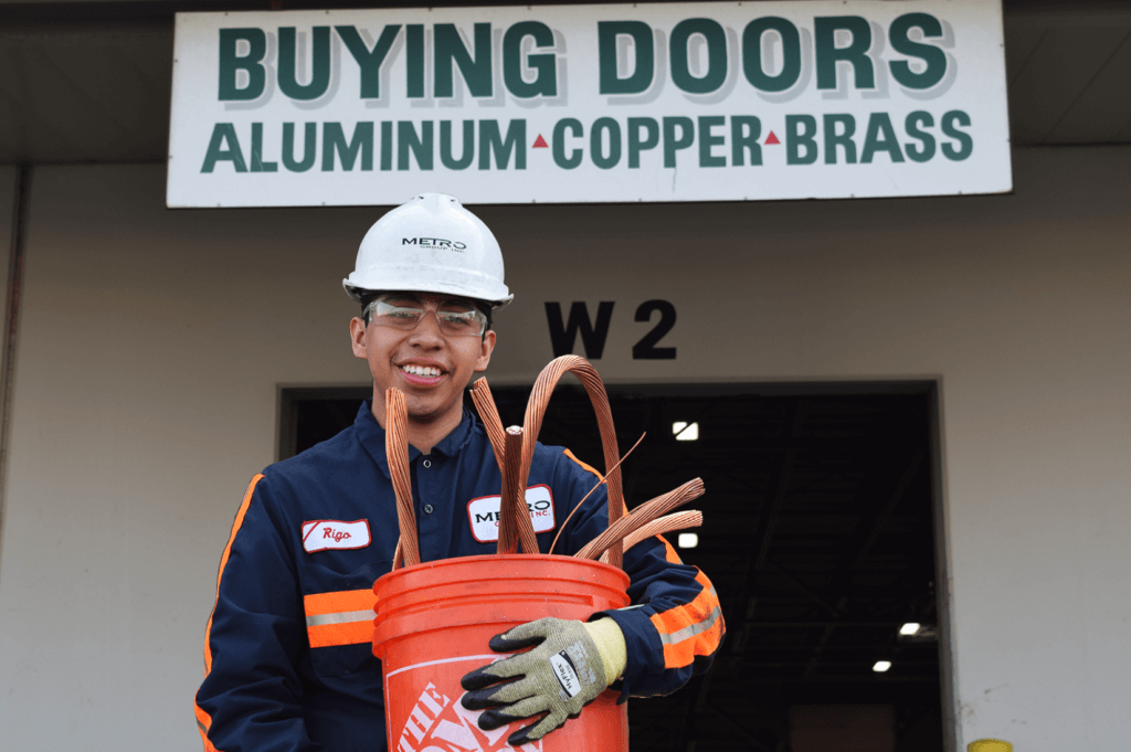 A man holding a bucket of copper, ready for recycling.