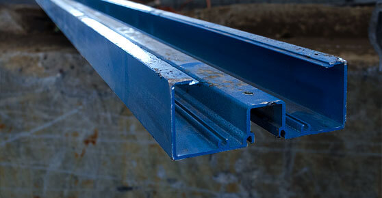 A blue steel beam hanging vertically from a concrete wall.