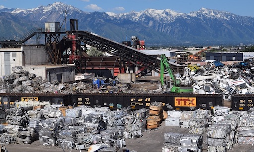 A pile of scrap metal in front of majestic mountains.